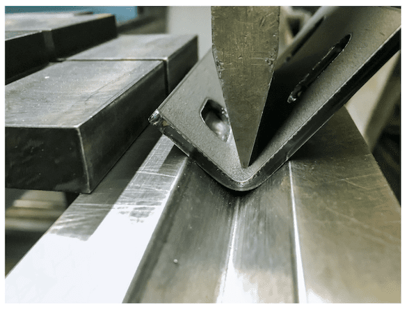 A piece of metal being bent through the stamping process